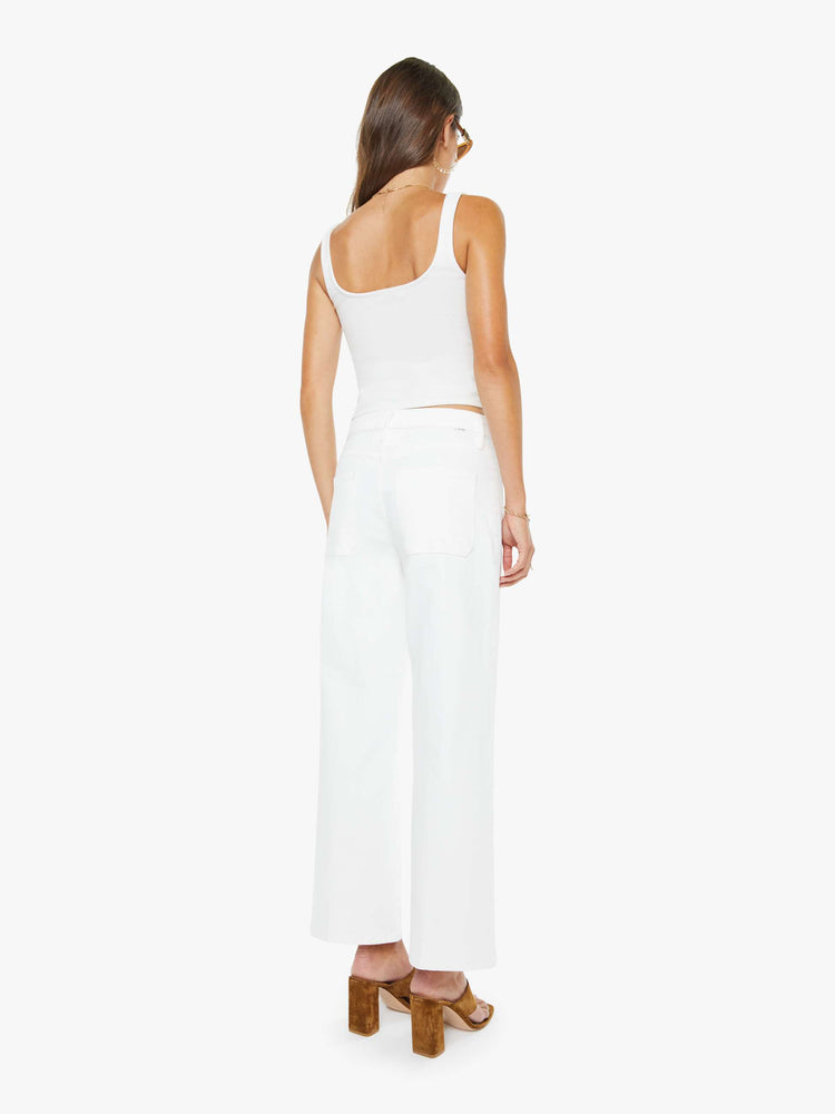 Back view of a woman in a white id-rise jeans with a loose fit, zip fly, wide leg, patch pockets and ankle-length inseam with a clean hem.