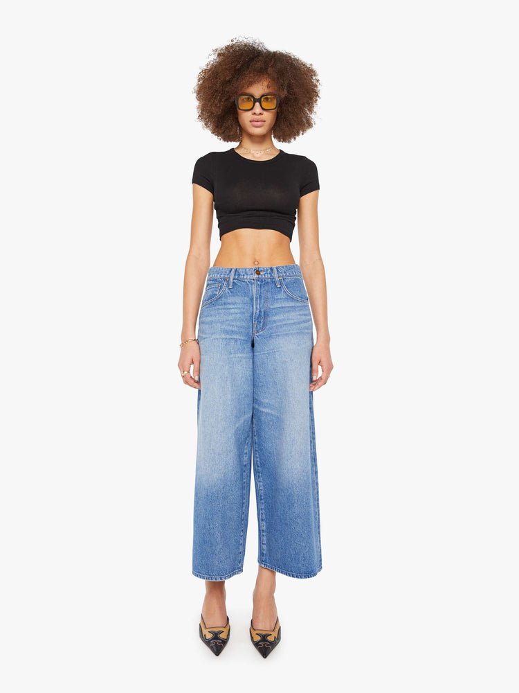 Front view of a woman in a med blue  high-waisted jeans have a low-slung fit, zip fly, loose wide-leg and a 28.5-inch inseam with a clean hem. 