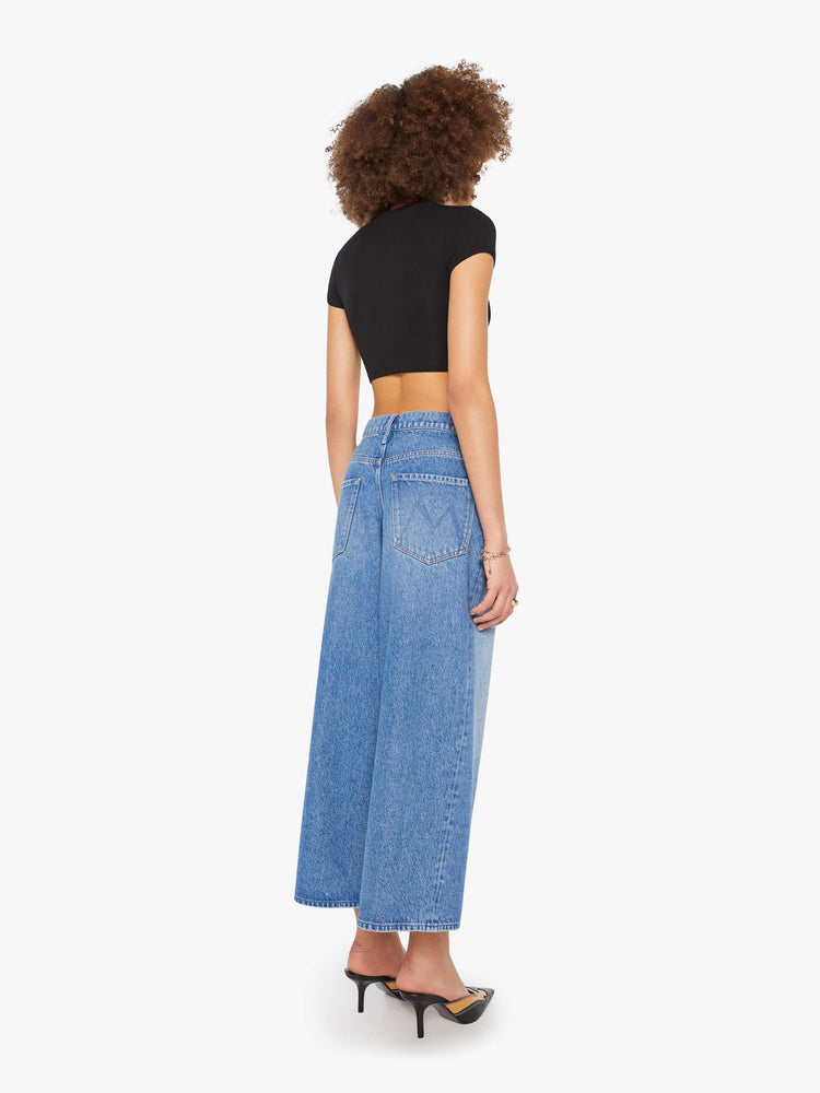 Back  view of a woman in a med blue  high-waisted jeans have a low-slung fit, zip fly, loose wide-leg and a 28.5-inch inseam with a clean hem. 