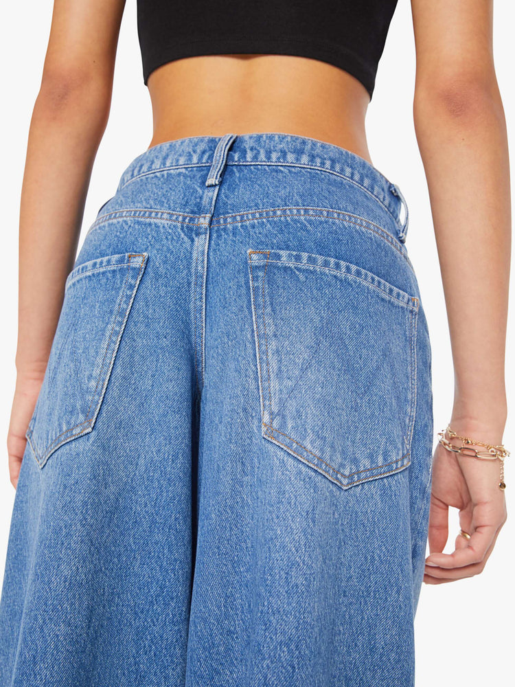 Close up back waist  view of a woman in a med blue  high-waisted jeans have a low-slung fit, zip fly, loose wide-leg and a 28.5-inch inseam with a clean hem. 