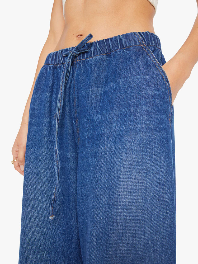 Close up view of a woman in a super high-waisted jeans have a loose straight leg, elastic drawstring waistband, zip fly and a 30-inch inseam with a clean hem.