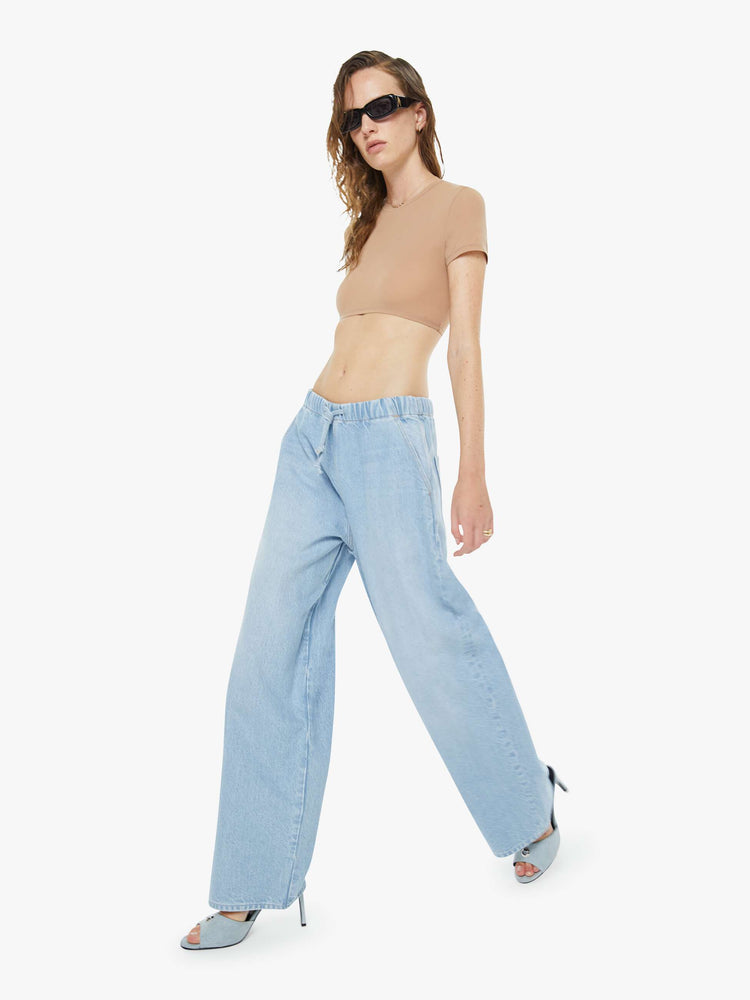 Walking view of a woman in a super high-waisted jeans have a loose straight leg, elastic drawstring waistband and a 30-inch inseam with a clean hem. 