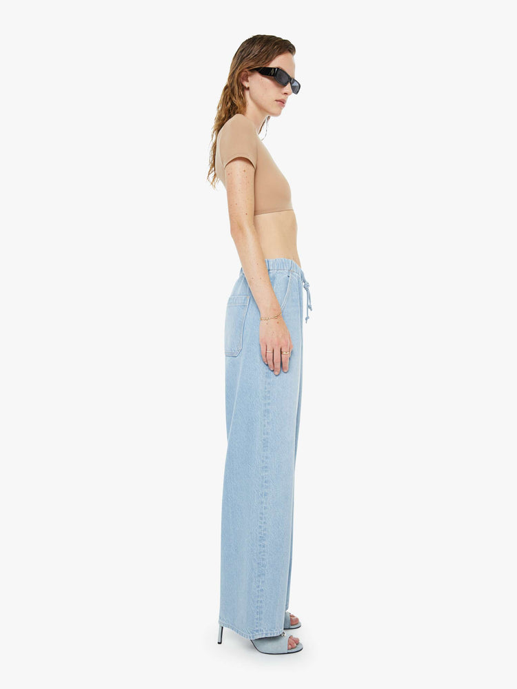 Side view of a woman in a super high-waisted jeans have a loose straight leg, elastic drawstring waistband and a 30-inch inseam with a clean hem. 