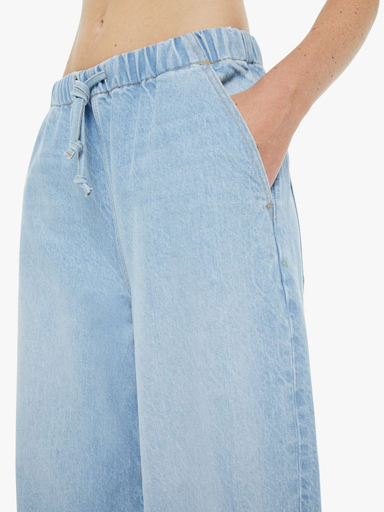 Close up view of a woman in a super high-waisted jeans have a loose straight leg, elastic drawstring waistband and a 30-inch inseam with a clean hem. 