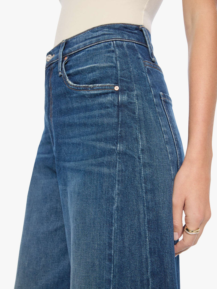 Close up view of a woman in a mid blue super high-waisted barrel-leg jeans with a relaxed fit, zip fly, inset panels on the outer seams, long 31-inch inseam and a clean hem. 