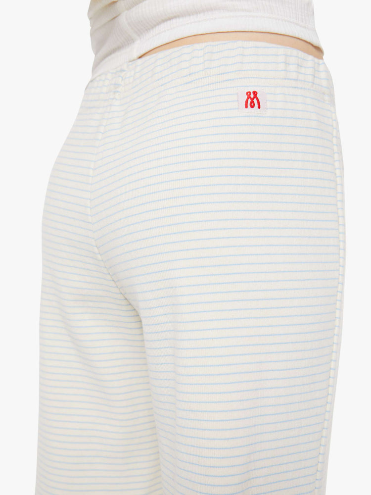 Back view of woman in a white with light blue horizontal stripes wide-leg pants with an elastic waistband and a loose, comfortable fit. 