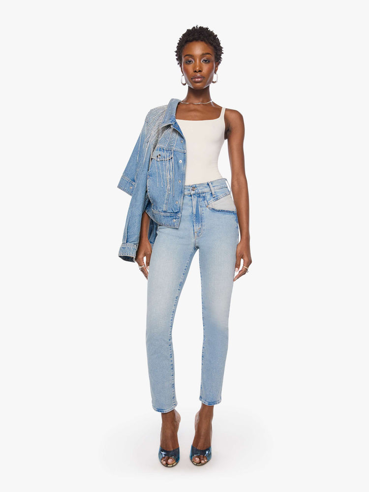 Front view of a woman in a light blue high-rise jean has a straight leg, zip fly, angled contrast cut-outs at the hips, a 29-inch inseam and a clean hem.