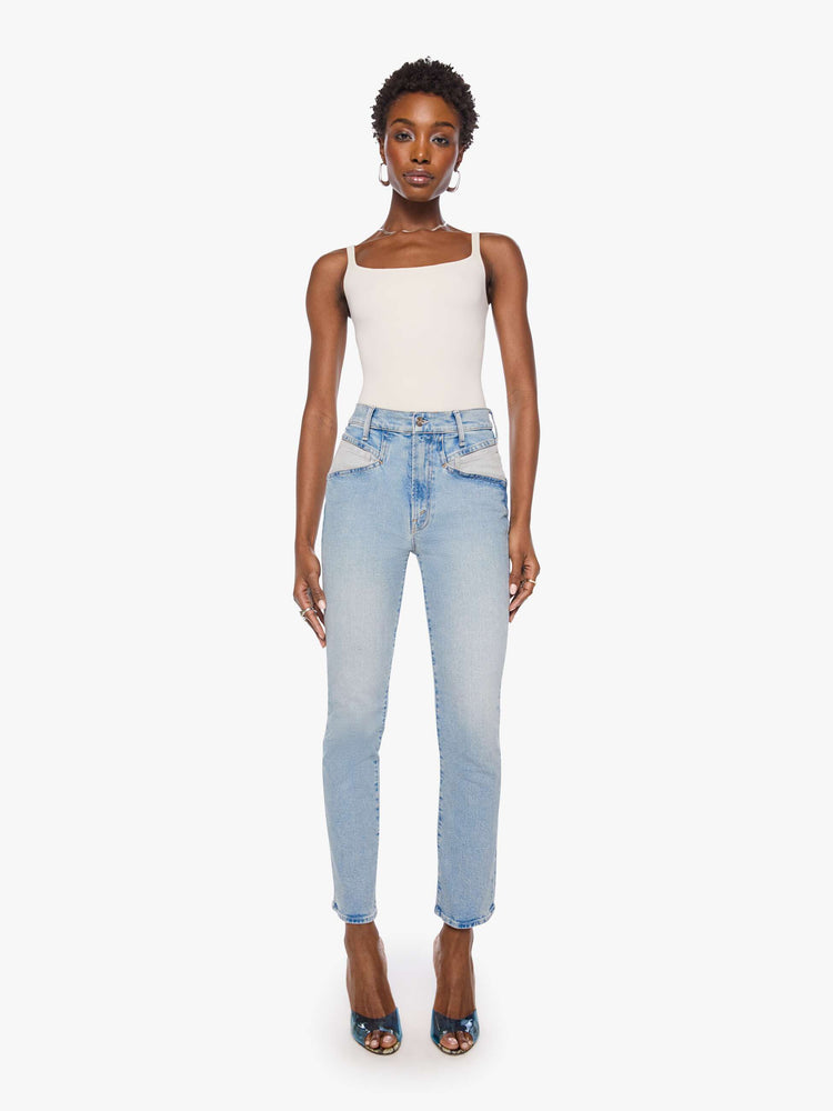Front view of a woman in a light blue high-rise jean has a straight leg, zip fly, angled contrast cut-outs at the hips, a 29-inch inseam and a clean hem.