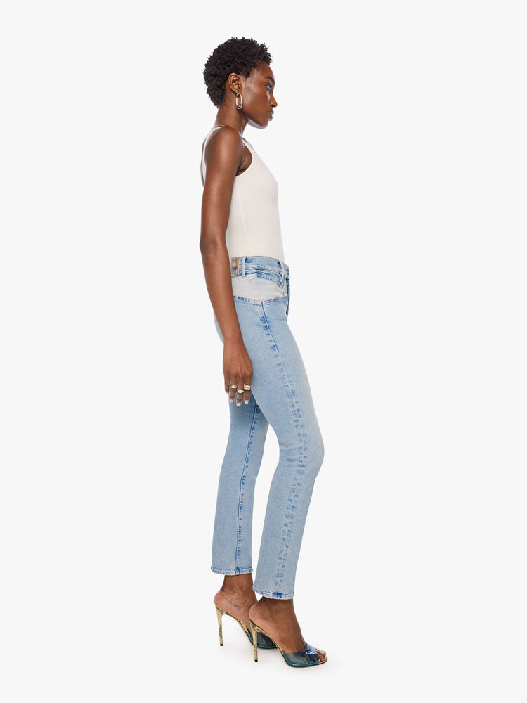 Side view of a woman in a light blue high-rise jean has a straight leg, zip fly, angled contrast cut-outs at the hips, a 29-inch inseam and a clean hem.