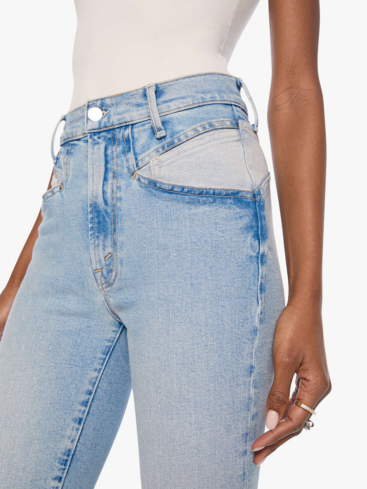 Close up view of a woman in a light blue high-rise jean has a straight leg, zip fly, angled contrast cut-outs at the hips, a 29-inch inseam and a clean hem.