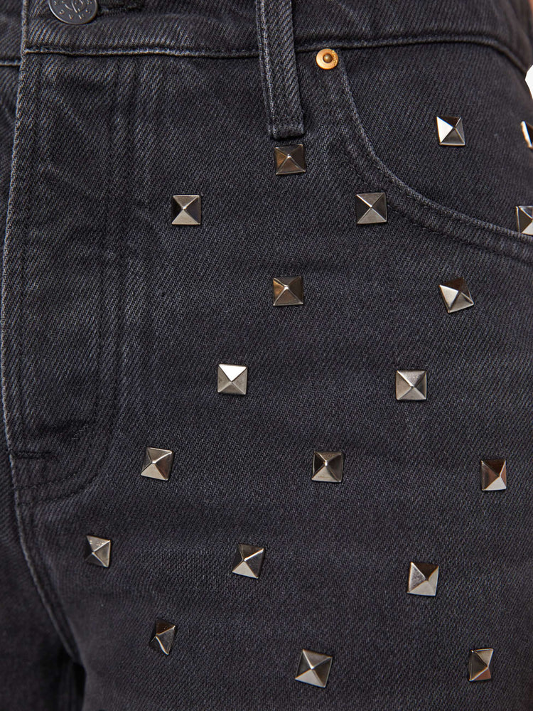 Front close up view of a woman wearing faded black denim pants with square studs throughout.