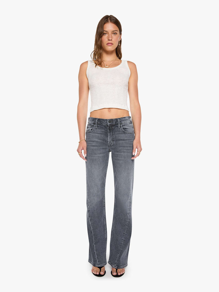 Front view of a woman in a washed grey mid-rise bootcut with a zip fly, looser leg, twisted outer seam and a long 32-inch inseam with a clean hem.