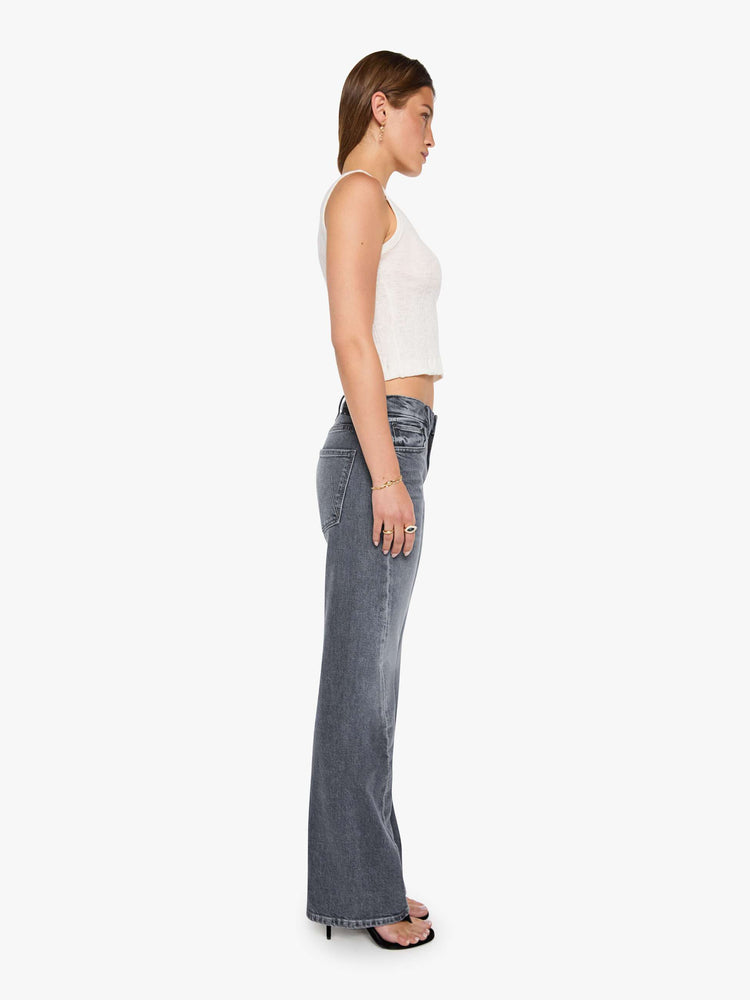 Side view of a woman in a washed grey mid-rise bootcut with a zip fly, looser leg, twisted outer seam and a long 32-inch inseam with a clean hem.