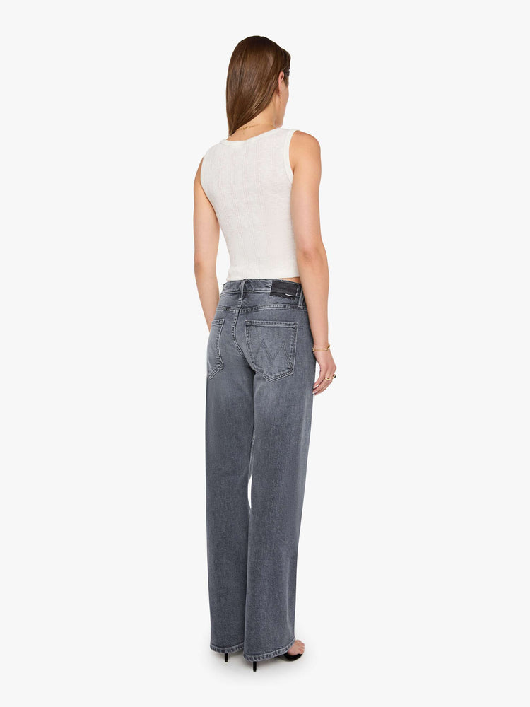 Back view of a woman in a washed grey mid-rise bootcut with a zip fly, looser leg, twisted outer seam and a long 32-inch inseam with a clean hem.
