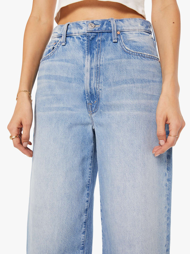 Close up view of a woman in a light blue high-waisted jeans with a wide barrel leg, zip fly and a 29-inch inseam with a frayed hem.