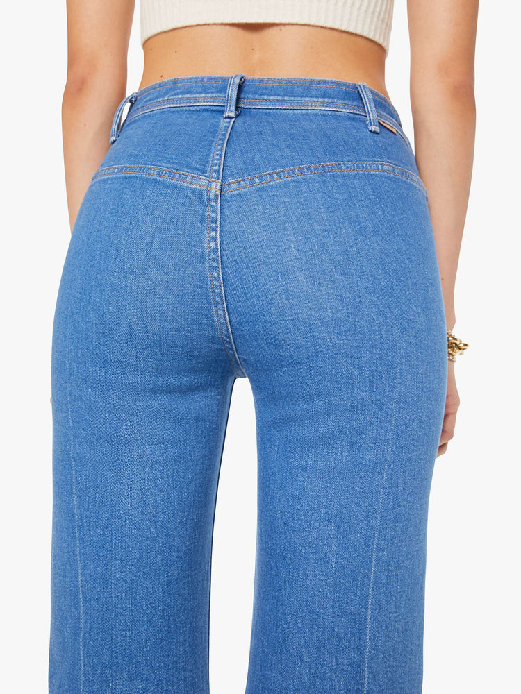 Back close up view of a woman in a mid blue wide leg jean features a high rise, buttoned waistband, zip fly, small patch pockets, long 32-inch inseam and a clean hem.