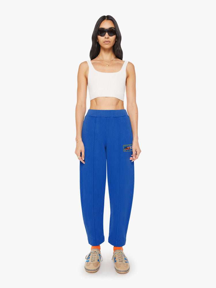 Front view of a woman in bright blue with colorful embroidery at the thigh barrel-leg sweatpants with an elastic waistband, pintuck details and a 28.25-inch inseam.