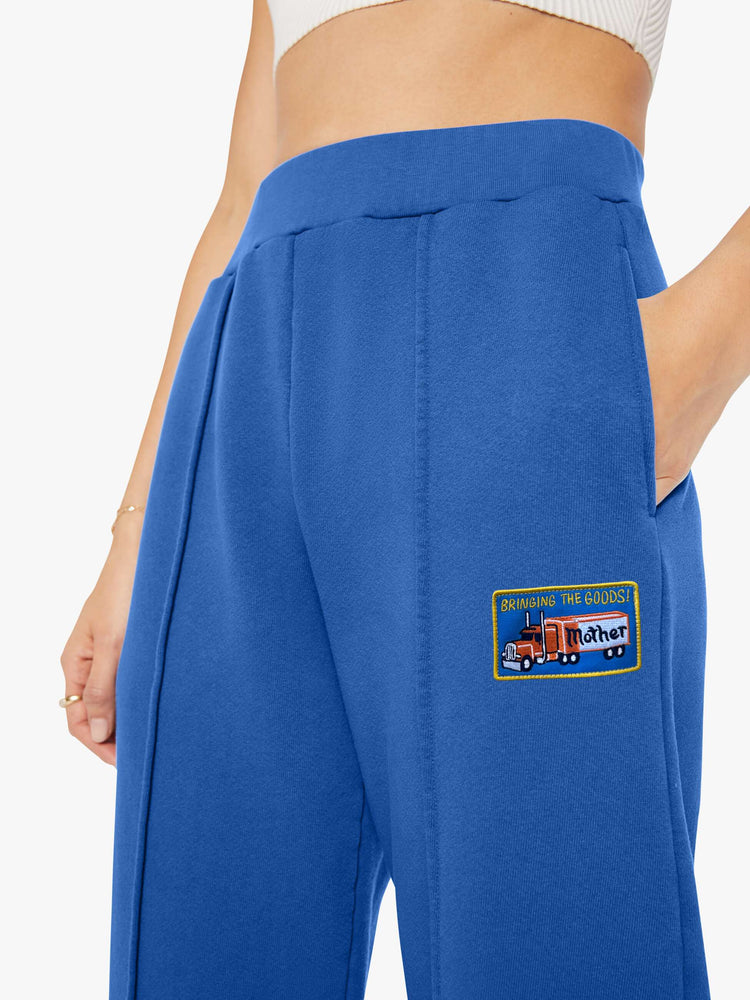 Close up view of a woman in bright blue with colorful embroidery at the thigh barrel-leg sweatpants with an elastic waistband, pintuck details and a 28.25-inch inseam.