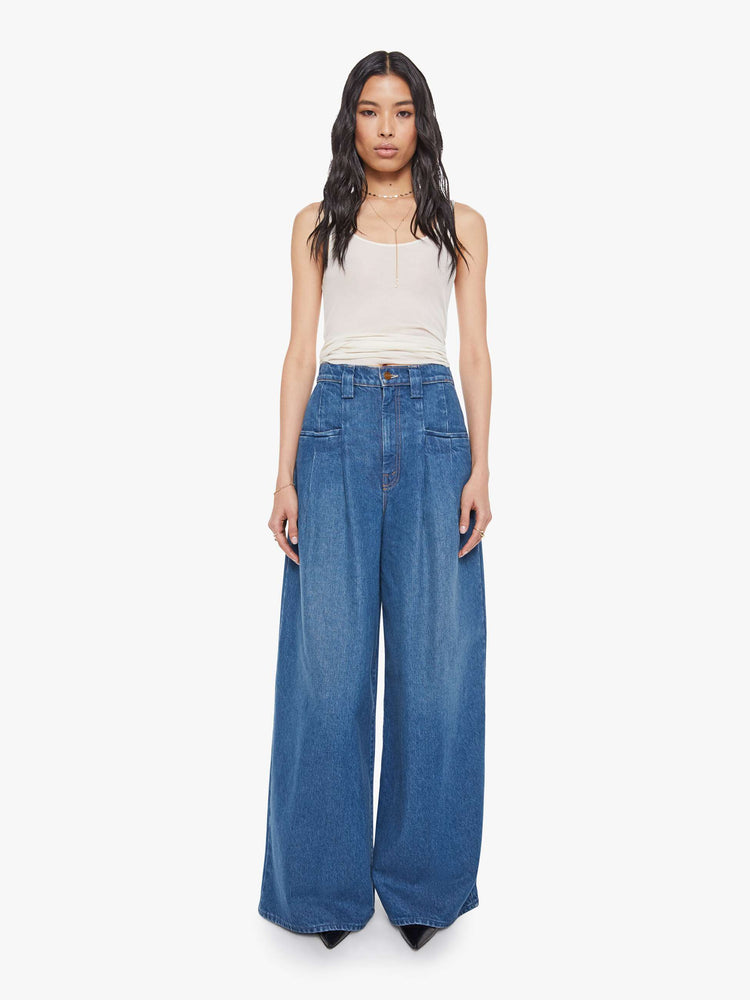 Front view of a woman in a super high rise wide-leg jeans are designed with slit pockets, pleated details, a zip fly and a long 31-inch inseam with a clean hem.