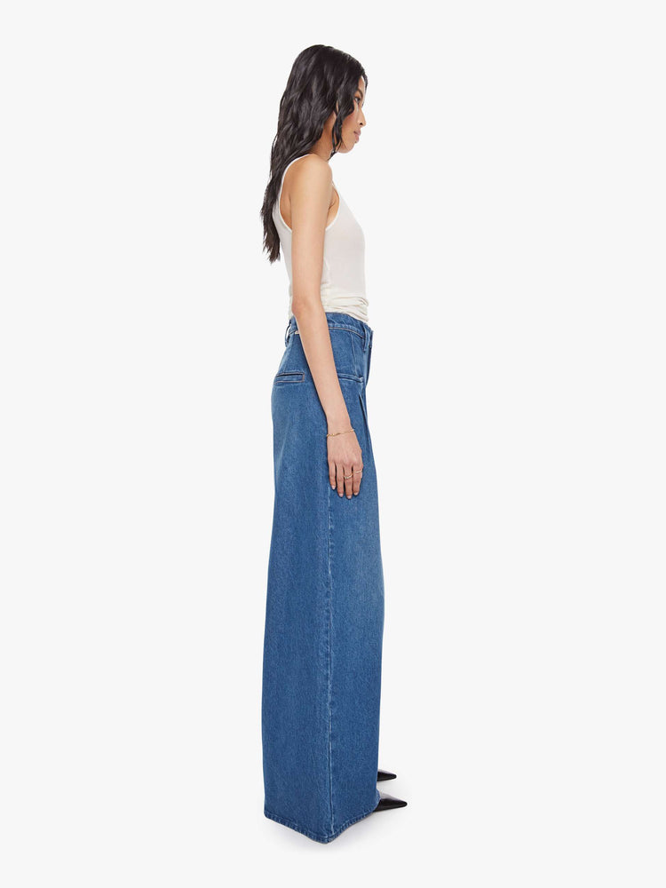 Side view of a woman in a super high rise wide-leg jeans are designed with slit pockets, pleated details, a zip fly and a long 31-inch inseam with a clean hem.