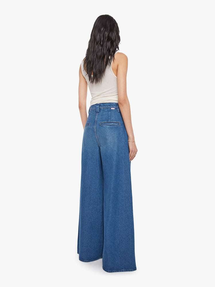 Back view of a woman in a super high rise wide-leg jeans are designed with slit pockets, pleated details, a zip fly and a long 31-inch inseam with a clean hem.