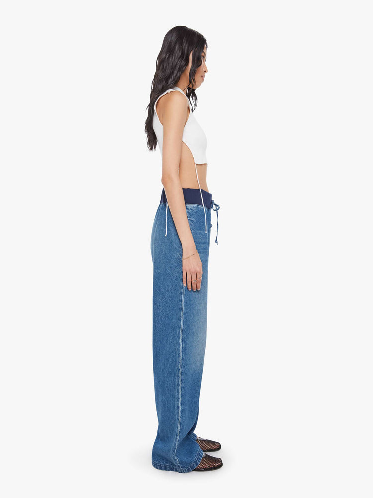 Side  view of a woman in a high-waisted wide-leg jeans are designed with a drawstring elastic waistband, slit pockets and a 32-inch inseam with a clean hem.