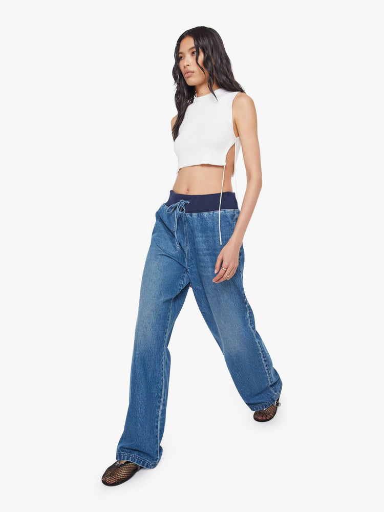 Walking  view of a woman in a high-waisted wide-leg jeans are designed with a drawstring elastic waistband, slit pockets and a 32-inch inseam with a clean hem.