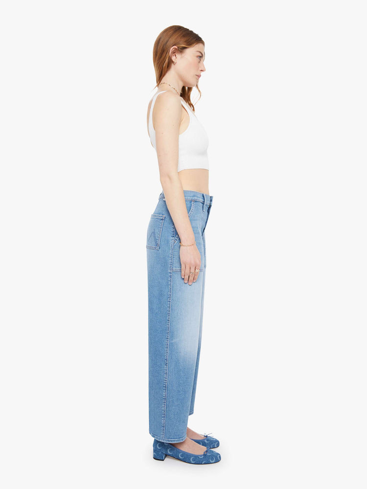 Side view of a woman in a light blue super high-waisted jeans with a loose fit, wide leg, zip fly, patch pockets and a 28.25-inch inseam with a clean hem.