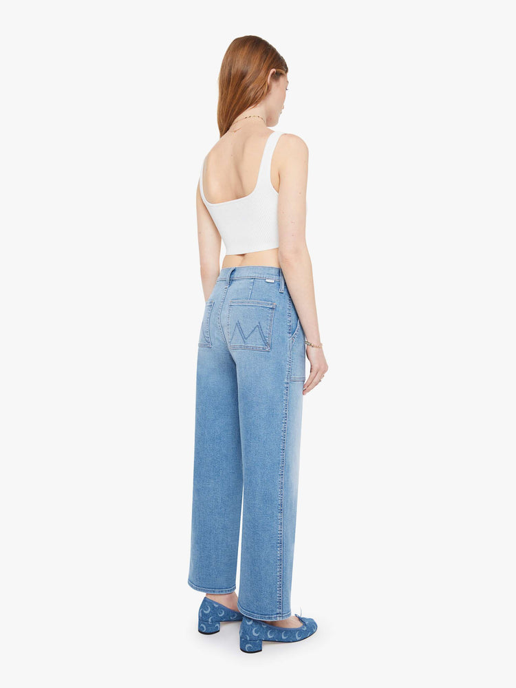 Back view of a woman in a light blue super high-waisted jeans with a loose fit, wide leg, zip fly, patch pockets and a 28.25-inch inseam with a clean hem.