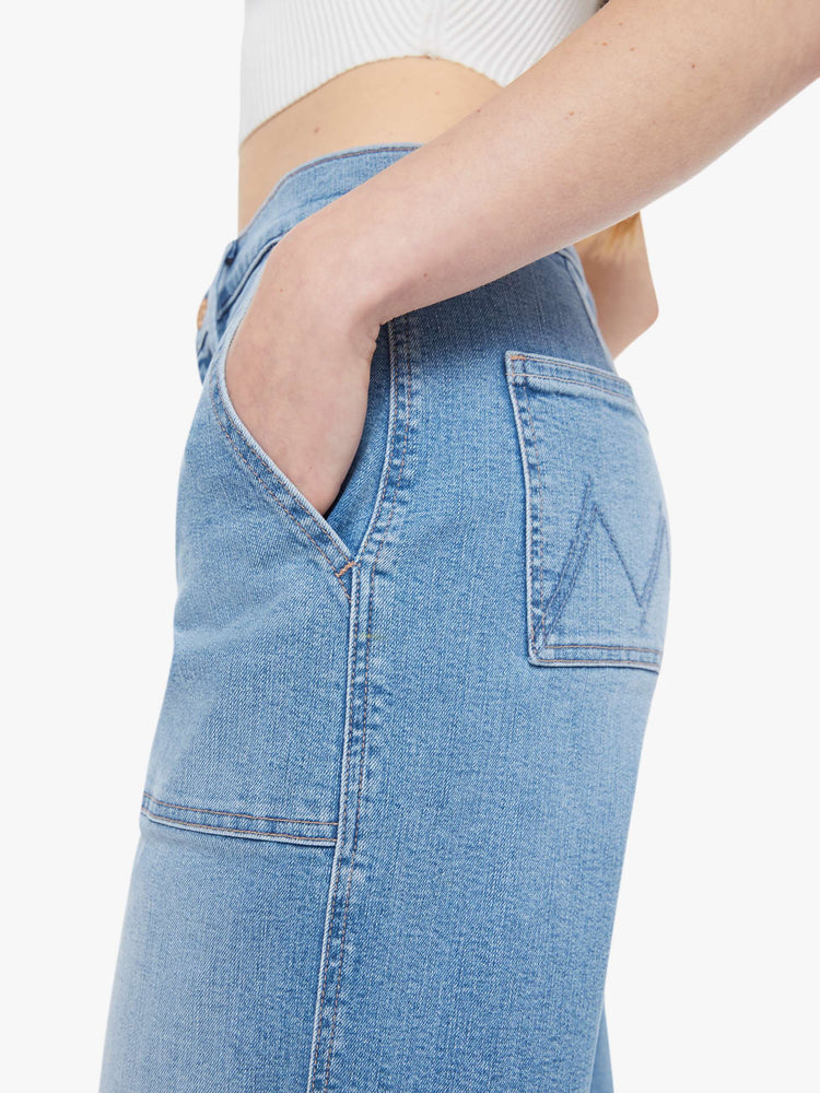 Close up view of a woman in a light blue super high-waisted jeans with a loose fit, wide leg, zip fly, patch pockets and a 28.25-inch inseam with a clean hem.