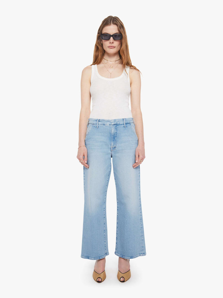 Front view of a woman in wide-leg pants designed to sit lower on the hips with a high rise, slit pockets, a zip fly, relaxed fit and an ankle-length inseam with a clean hem.