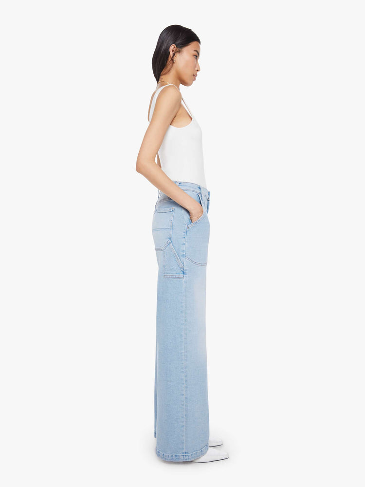 Side view of a woman in a light blue wide-leg jeans with a super high rise, zip fly, utility-inspired patch pockets, hammer loop, angled seamed details across the front and a long 32-inch inseam with a clean hem.