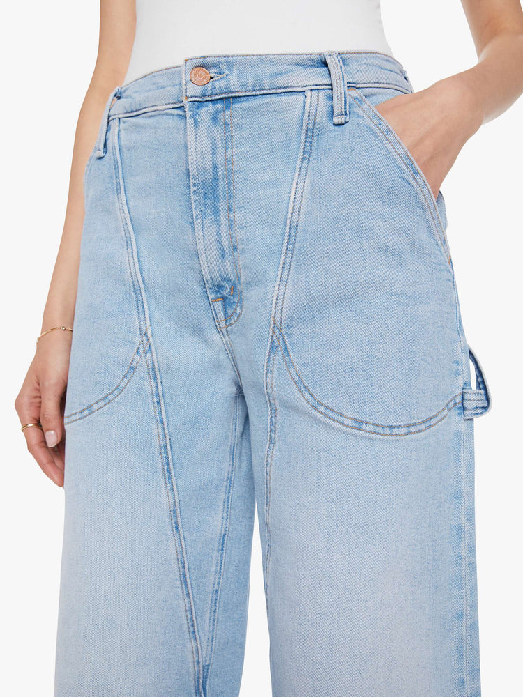 Close up view of a woman in a light blue wide-leg jeans with a super high rise, zip fly, utility-inspired patch pockets, hammer loop, angled seamed details across the front and a long 32-inch inseam with a clean hem.