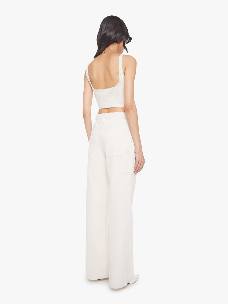 Back view of a woman in a creamy white wide-leg jeans with a super high rise, zip fly, utility-inspired patch pockets, a hammer loop, angled seamed details across the front and a long 32-inch inseam with a clean hem.