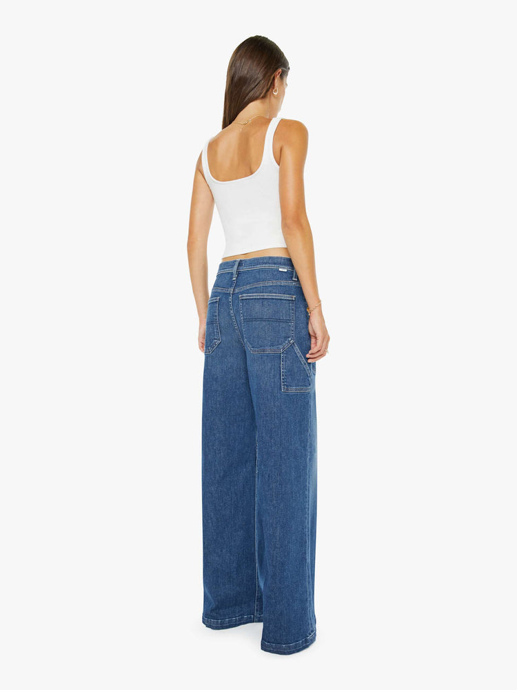Back view of a woman in a wide-leg jeans with a super high rise, zip fly, utility-inspired patch pockets, a hammer loop, angled seamed details across the front and a long 32-inch inseam with a clean hem.