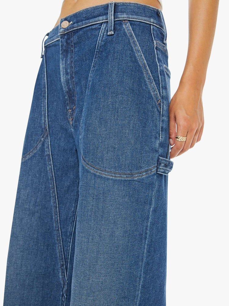 Close up view of a woman in a wide-leg jeans with a super high rise, zip fly, utility-inspired patch pockets, a hammer loop, angled seamed details across the front and a long 32-inch inseam with a clean hem.