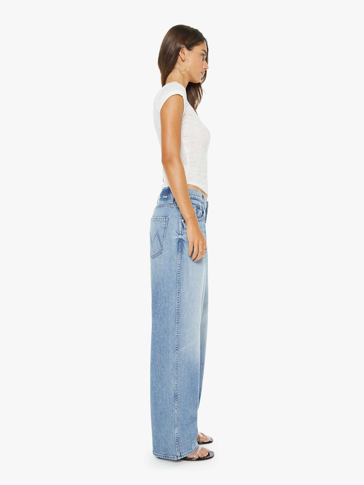 Side view of a woman in a light blue jeans designed to sit lower on the hips with a button fly, a 30-inch inseam, clean hem and slightly tapered leg.