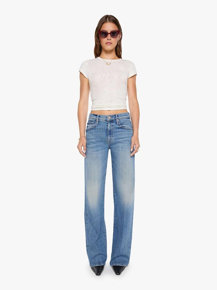 Front view of a woman in a mid blue wide-leg pants with a subtle barrel shape, a zip fly, mid rise and a 32-inch inseam with a clean hem.