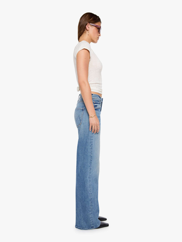 Side view of a woman in a mid blue wide-leg pants with a subtle barrel shape, a zip fly, mid rise and a 32-inch inseam with a clean hem.