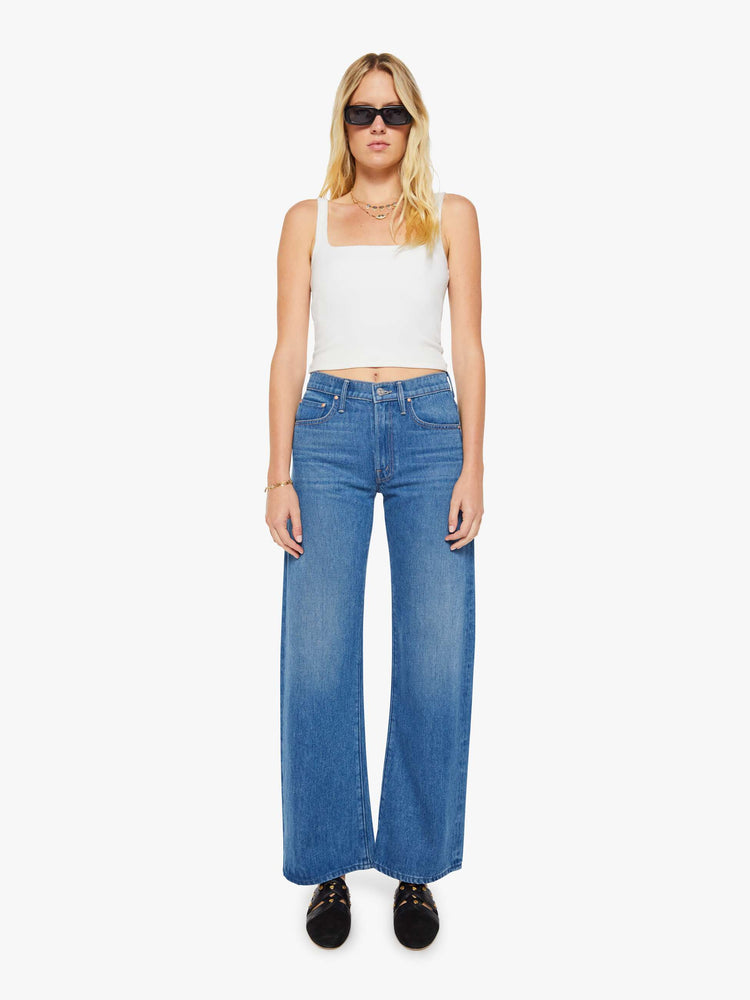 Front view of a woman in a mid blue wide-leg pants with a zip fly, mid rise and 33-inch inseam with a clean hem. 