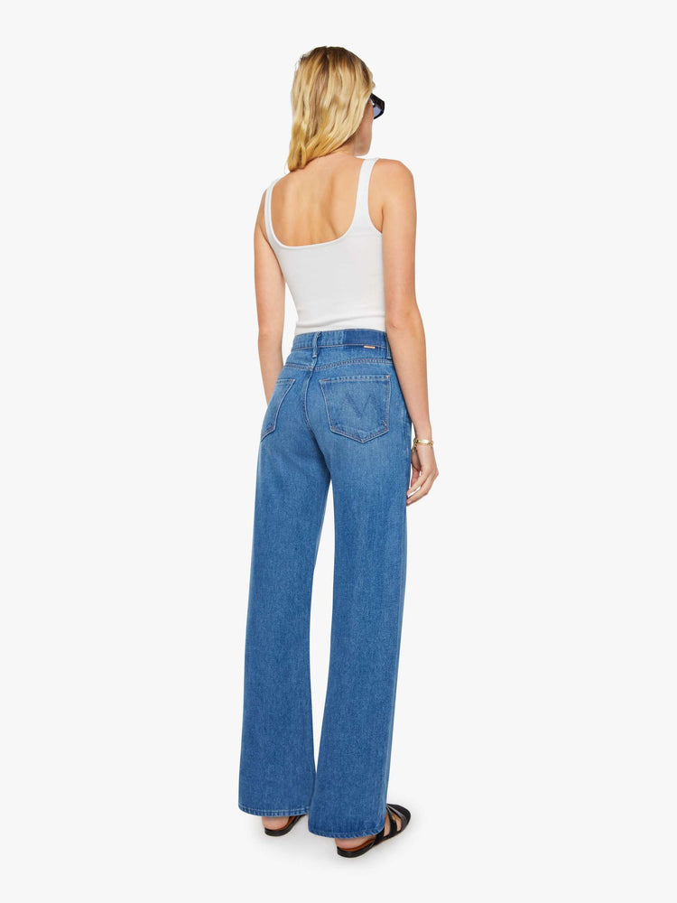 Back view of a woman in a mid blue wide-leg pants with a zip fly, mid rise and 33-inch inseam with a clean hem. 