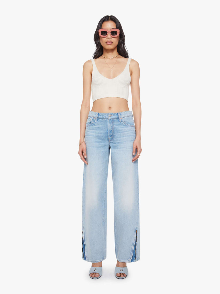 Front view of a woman in a light blue high-waisted jeans with a loose wide leg, zip fly and a long 34-inch inseam with a clean hem that can be zipped for a more tapered fit.