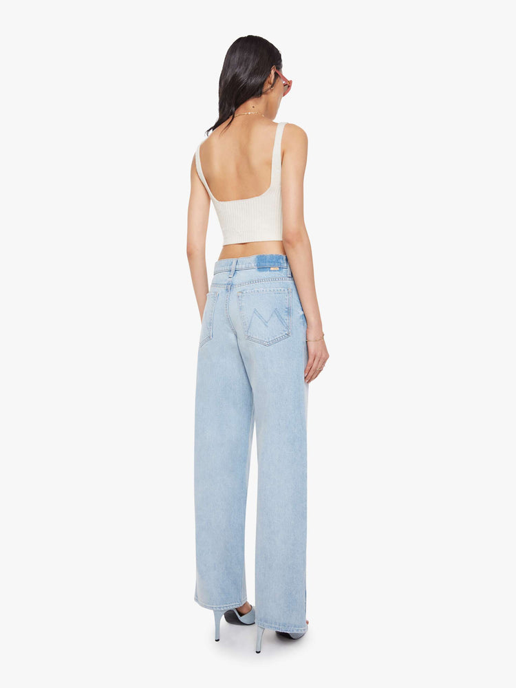 Back view of a woman in a light blue high-waisted jeans with a loose wide leg, zip fly and a long 34-inch inseam with a clean hem that can be zipped for a more tapered fit.