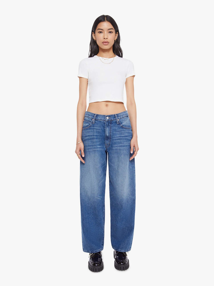 Front view of a woman in a mid blue   jeans designed to sit lower on the hips with a 28-inch inseam, zip fly, clean hem and slightly tapered leg. 