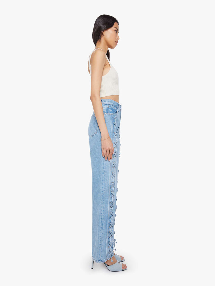 Side view of a woman in a light blue super high-rise jeans with a loose fit and a wide leg with tied details down the front, a zip fly and 32-inch inseam with a clean hem.