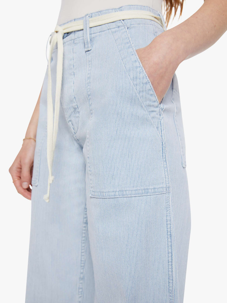 Close up  view of a woman in a light blue with white vertical stripes high-waisted jeans with a loose wide leg, utility-inspired patch pockets, a button fly, 30-inch inseam and a clean hem.