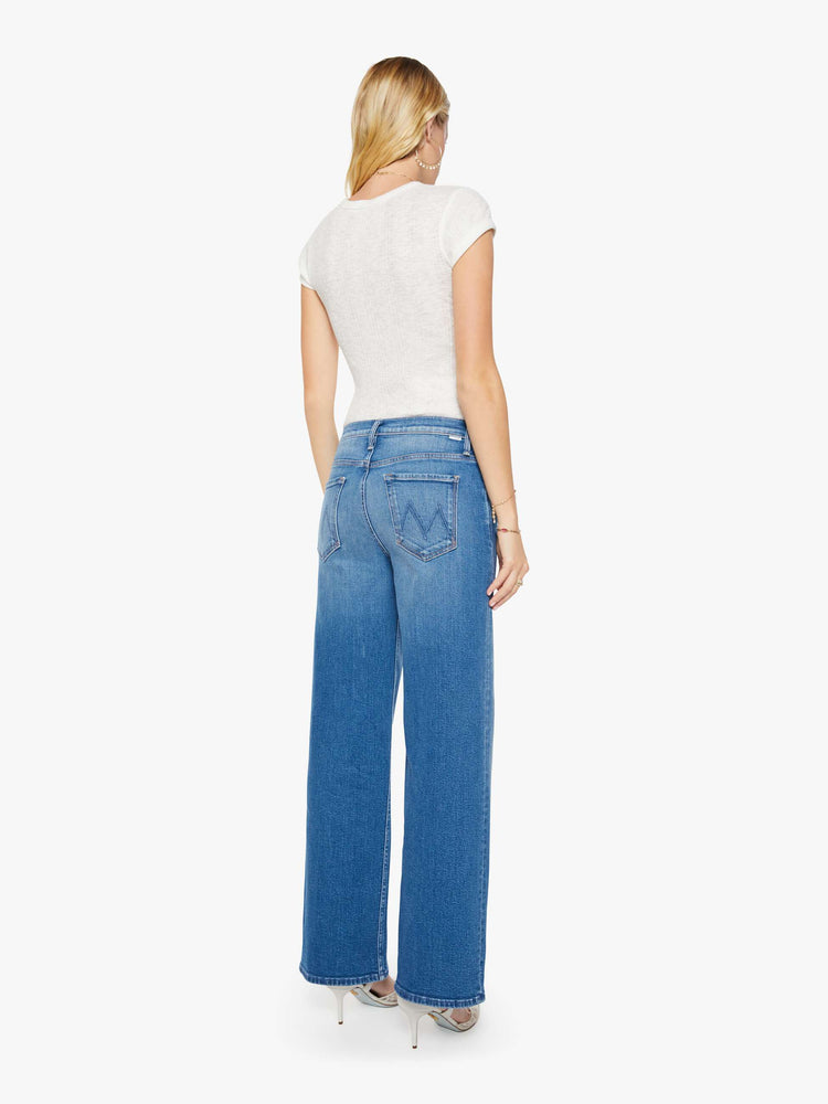 Back view of a woman in a mid blue high-waisted wide leg jeans with a button fly, a long 32-inch inseam and loose, low-slung fit.