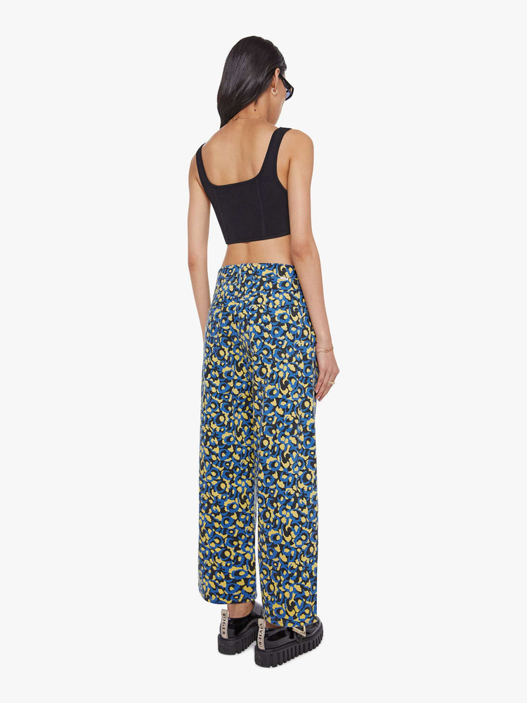 Back view of a woman in lower on the hips  jean with an ankle-length inseam, zip fly, clean hem and slightly tapered leg in a a blue, yellow and black leopard print.