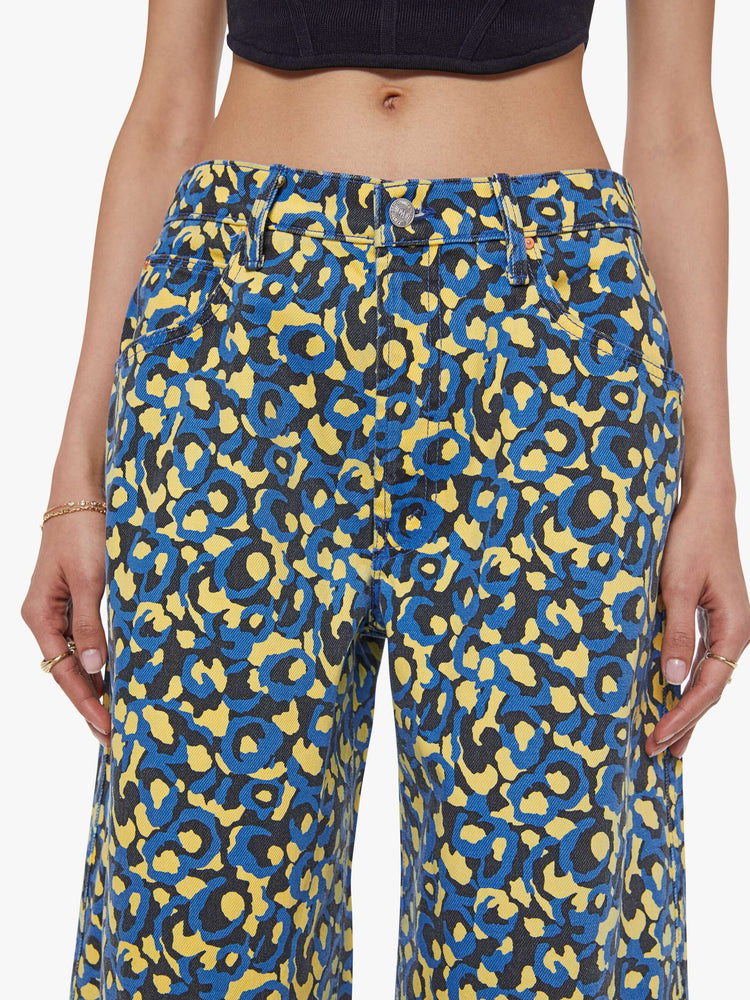 Close up view of a woman in lower on the hips  jean with an ankle-length inseam, zip fly, clean hem and slightly tapered leg in a a blue, yellow and black leopard print.