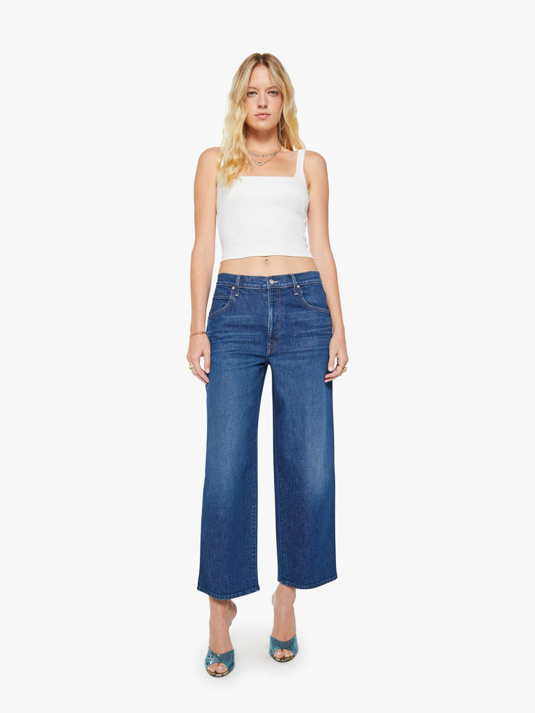 Front view of a woman in a dark blue jeans designed to sit lower on the hips with an ankle-length inseam, zip fly, clean hem and slightly tapered leg.